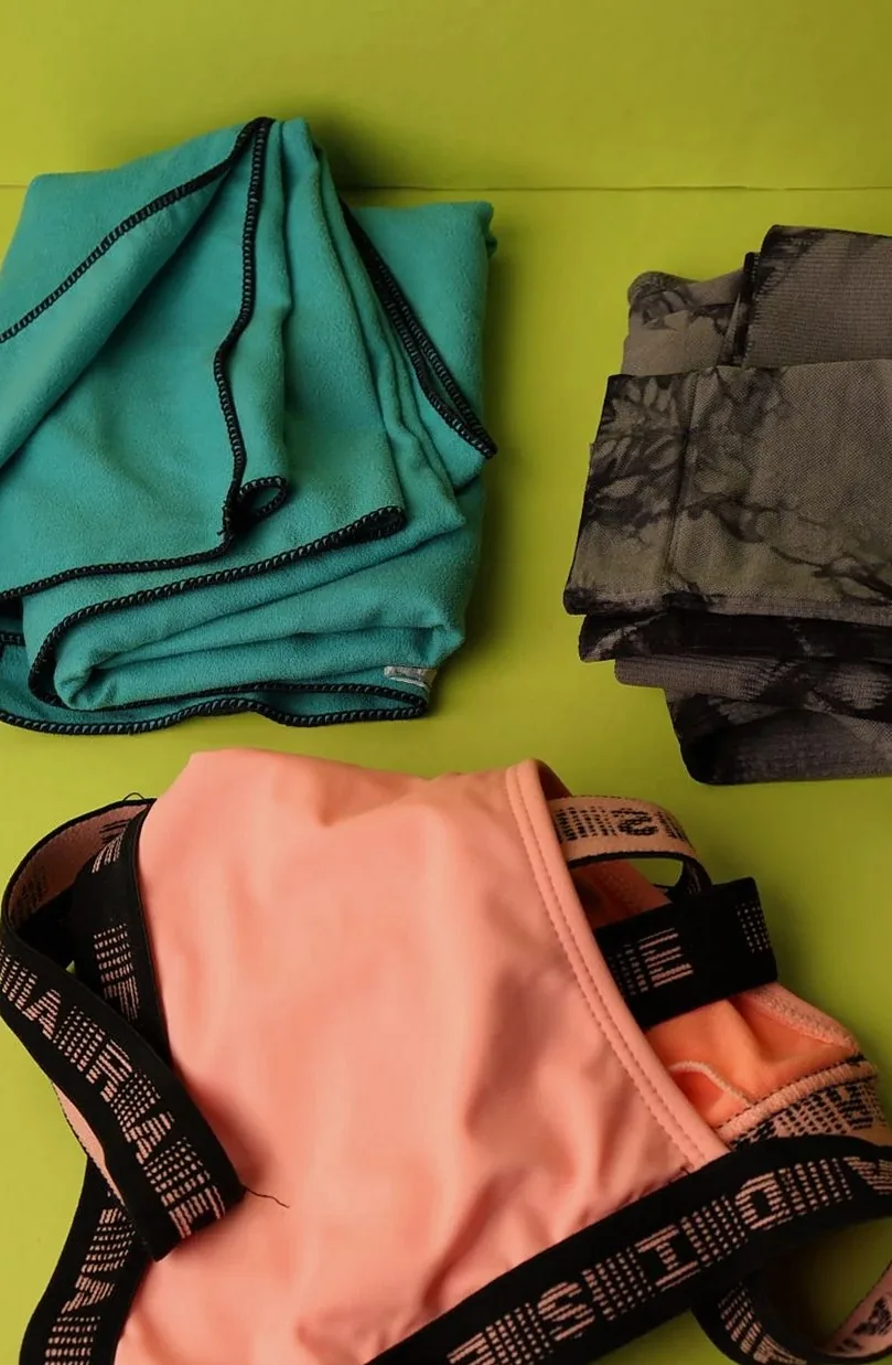 Flat lay of colorful clothing items on a bright green surface.